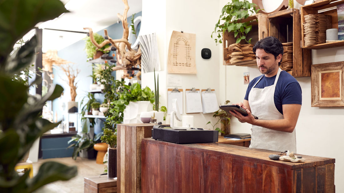 A business owner with a smart thermostat in the background