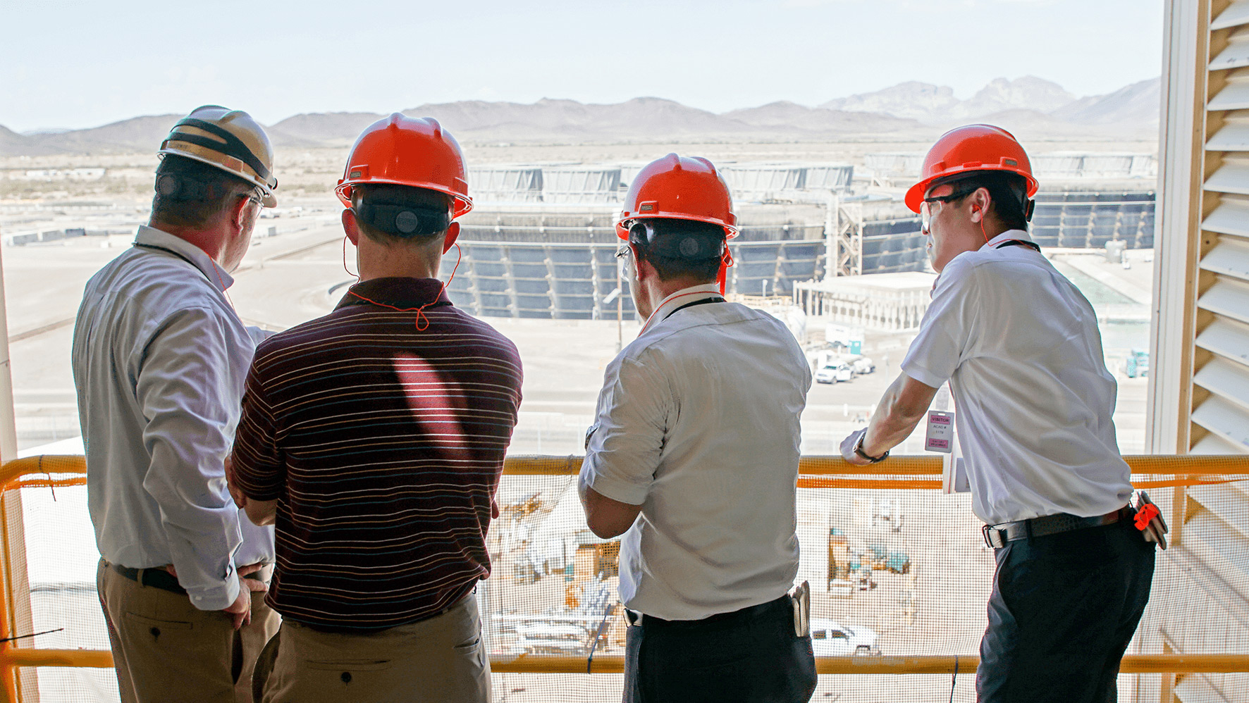 Three APS employees looking over a balcony.