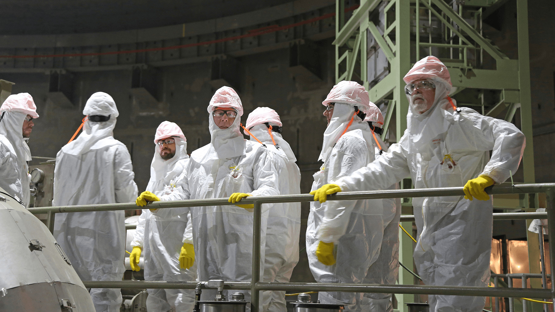 Professionals in clean suits looking over the balcony of a warehouse facility.