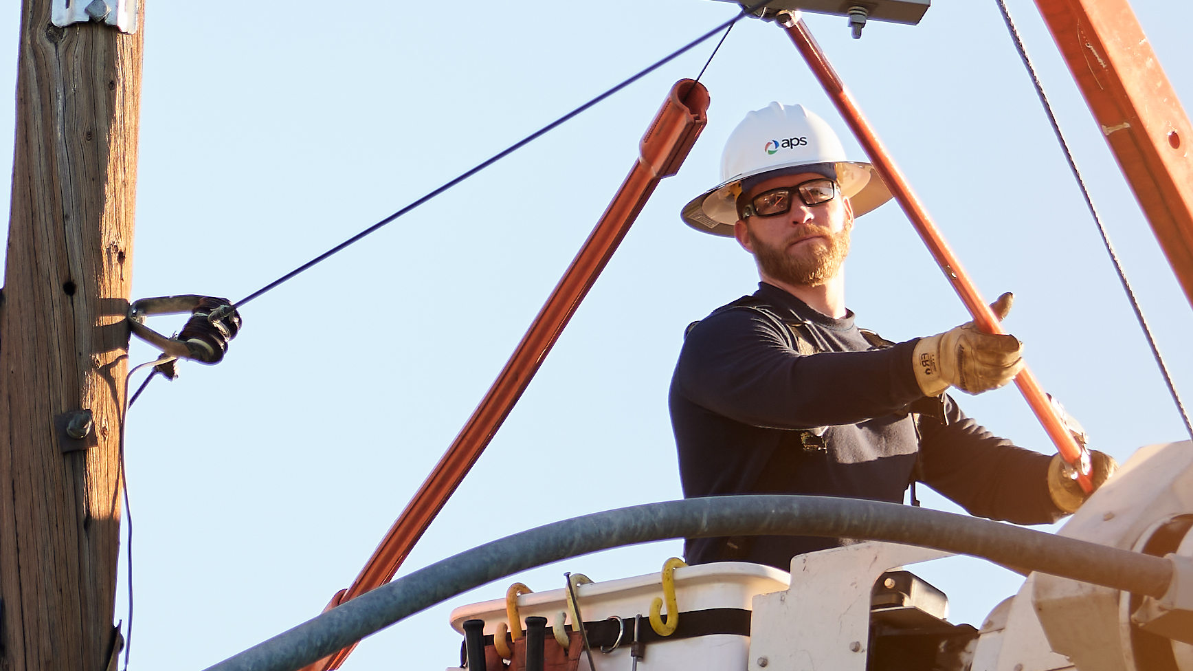 A close-up of a lineman in a bucket truck working on an electrical pole.