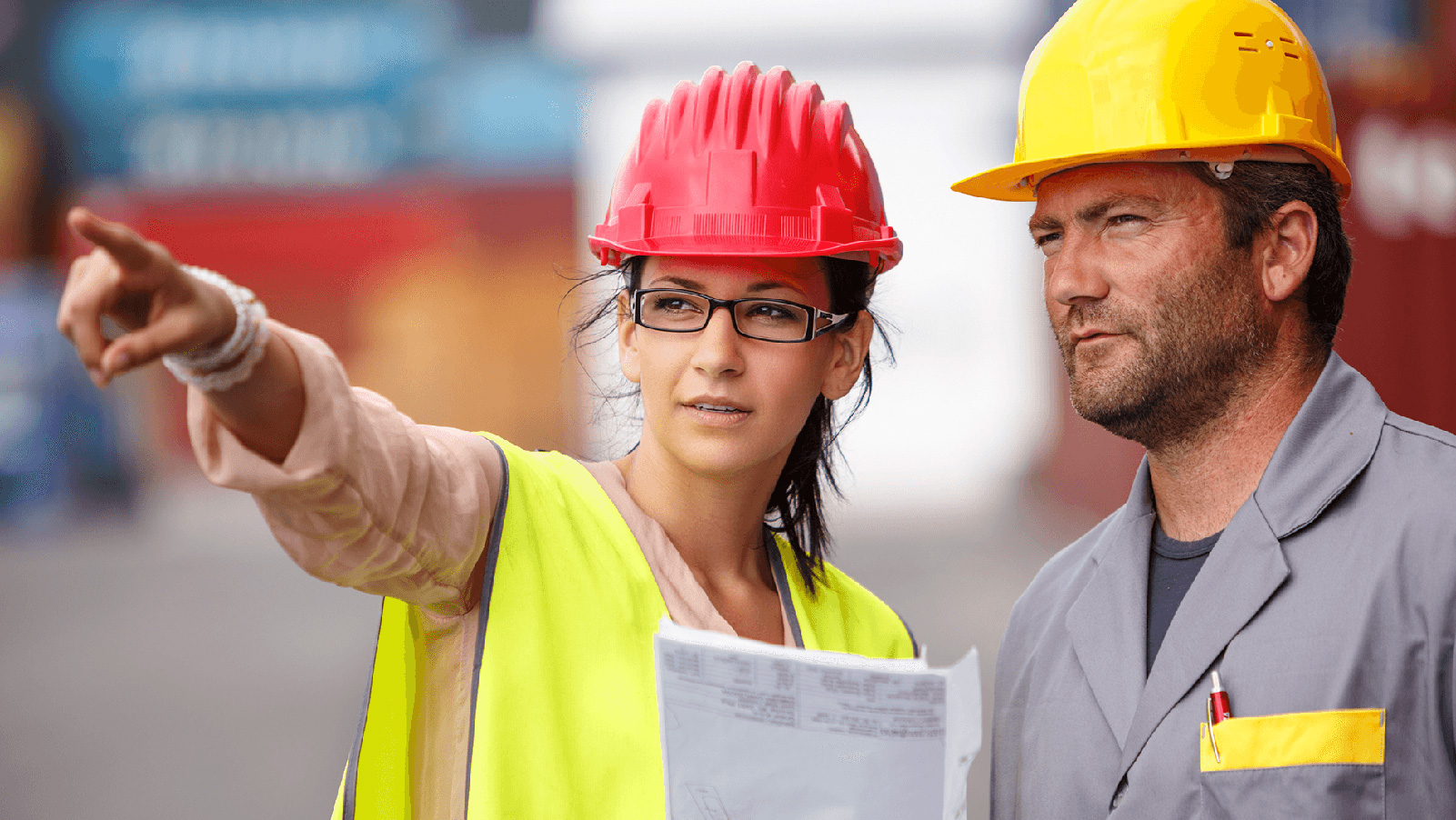 Two construction workers pointing and looking at a site.