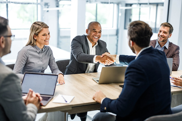 Smiling people in a meeting shaking hands across the table