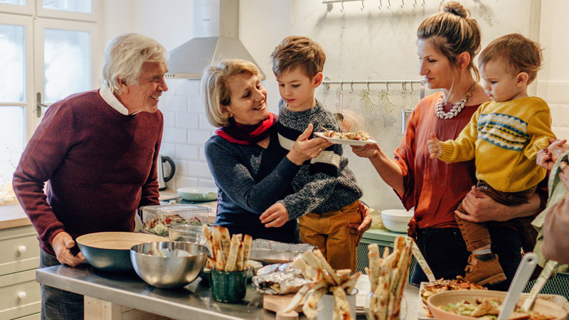 A family in the kitchen standing over a meal